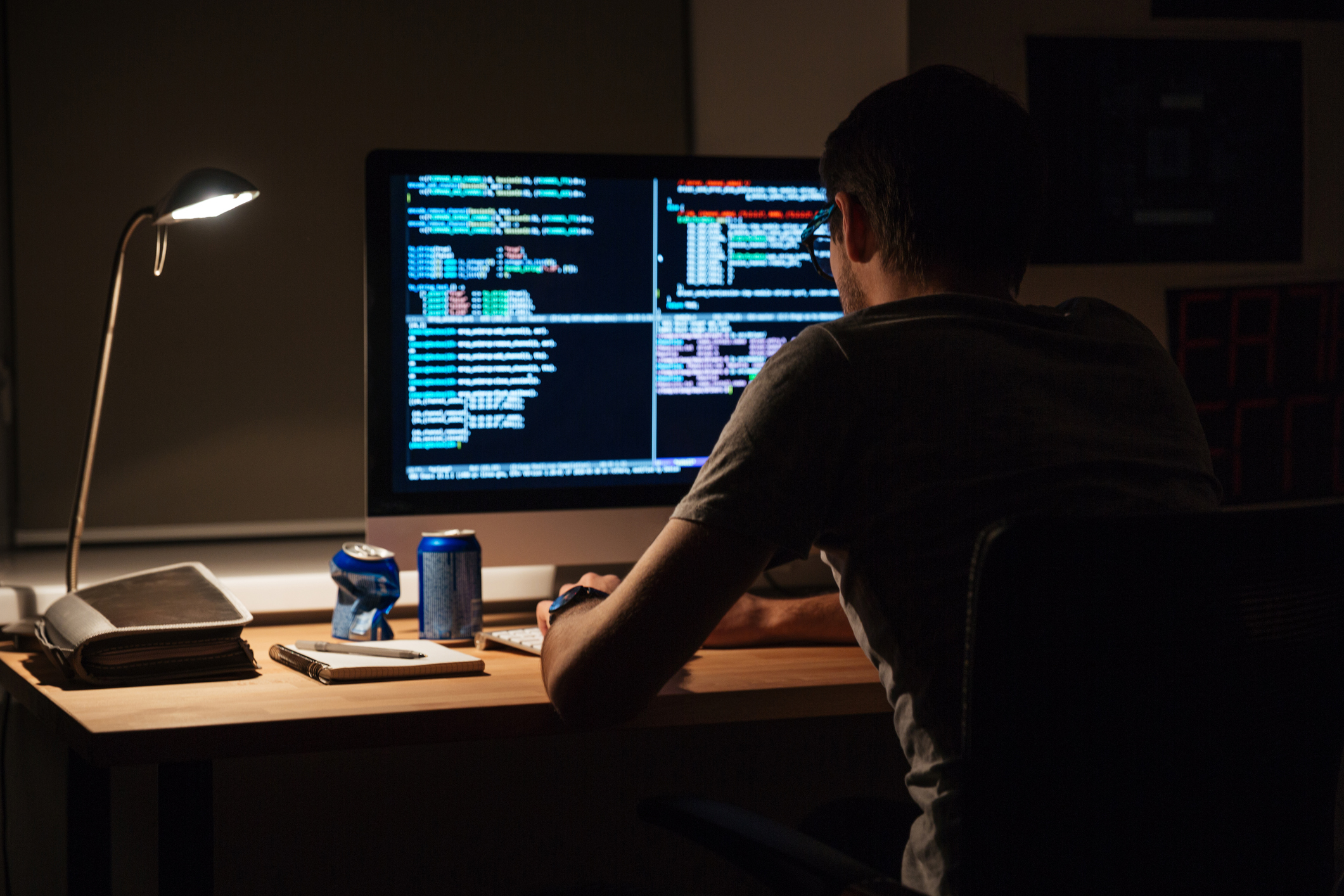Back view of modern programmer sitting and writing code Man coding on computer at night.